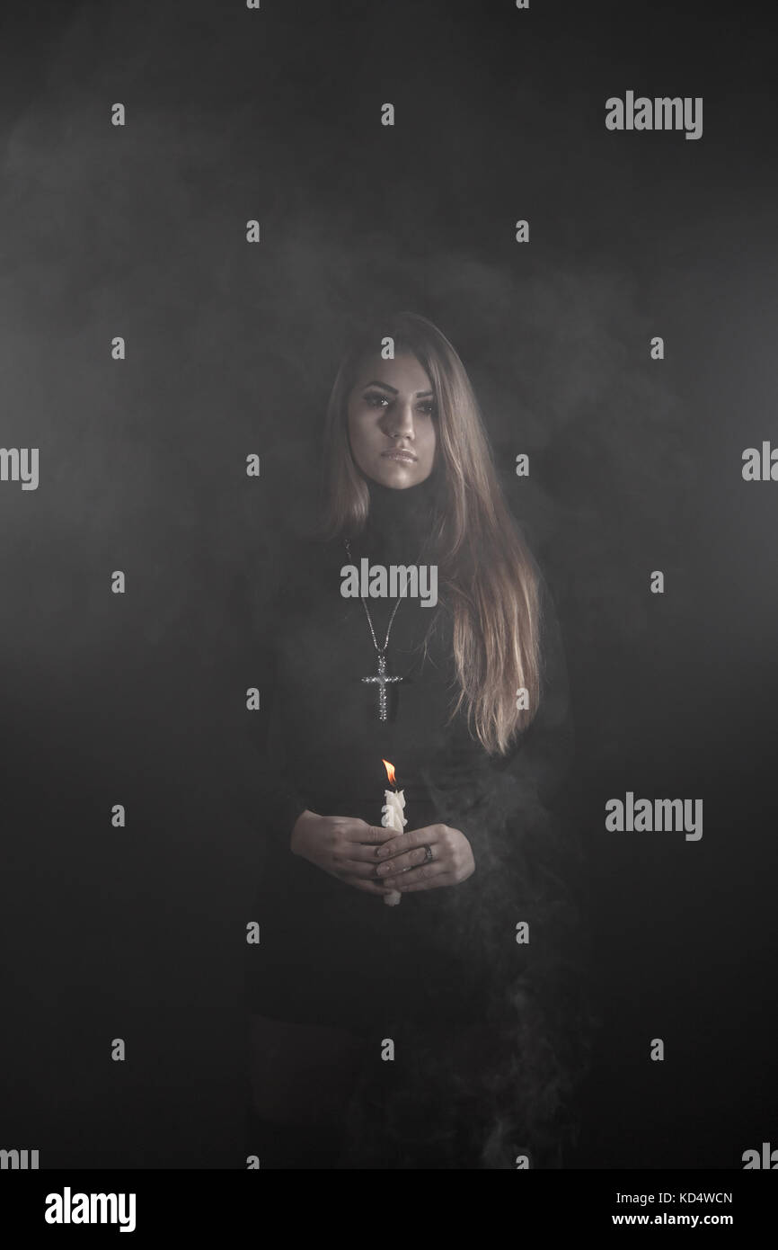 Einsame junge Frau mit einer Kerze in einer Rauch Stockfoto