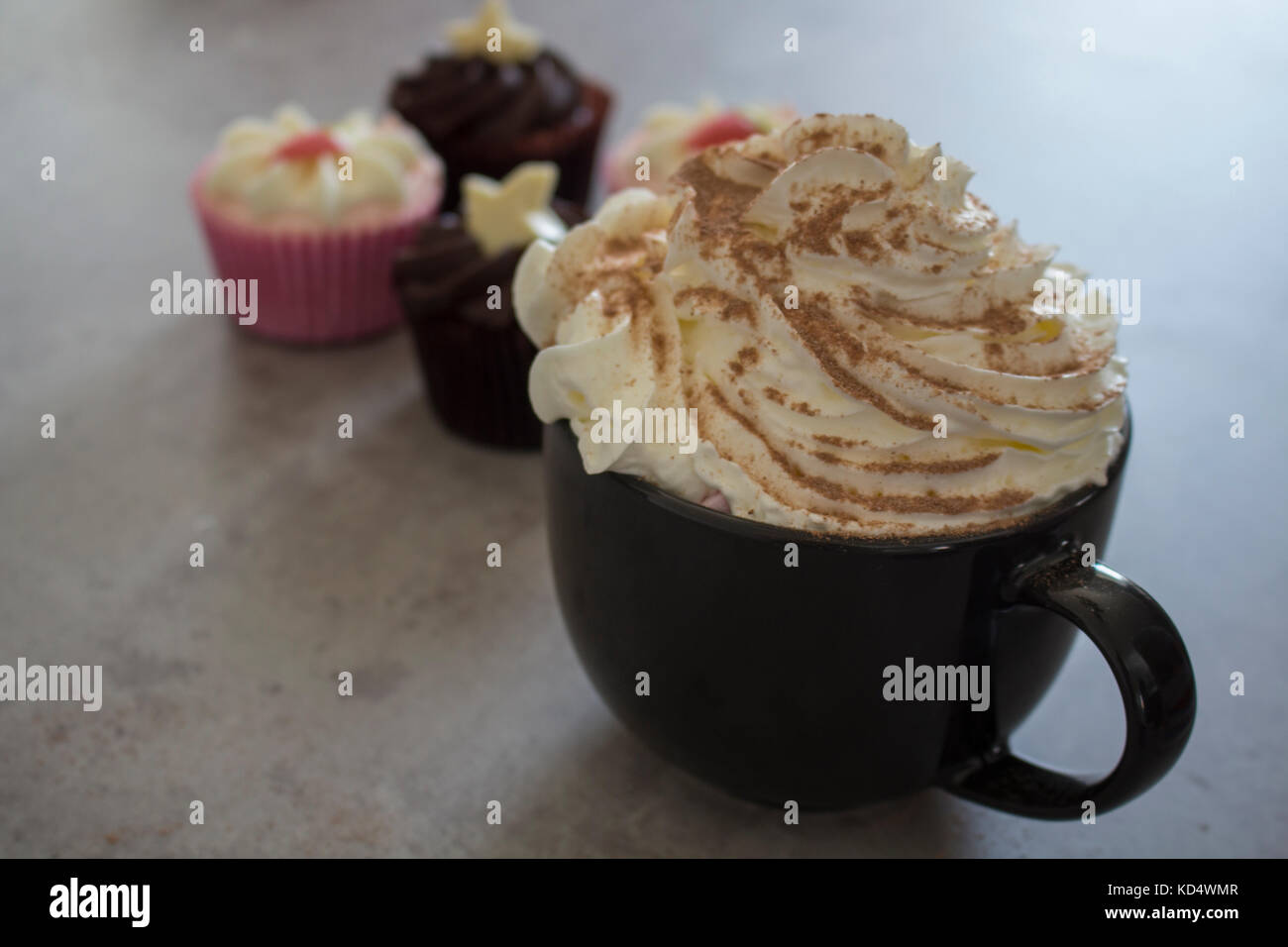 Erdbeer und Schokolade cupcakes durch heiße Schokolade mit Sahne und Schokolade abstauben begleitet. Stockfoto