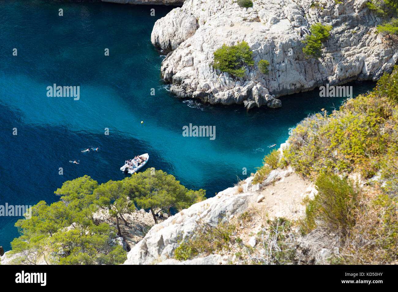 Calanque de Sugiton, Boot in einer Bucht, Menschen schwimmen in azurblauem Meerwasser, Calanques Nationalpark, Frankreich Stockfoto