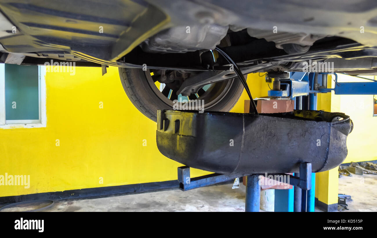 Mechaniker Ablassen von Motoröl aus ein Auto für einen Ölwechsel an einem Auto Shop