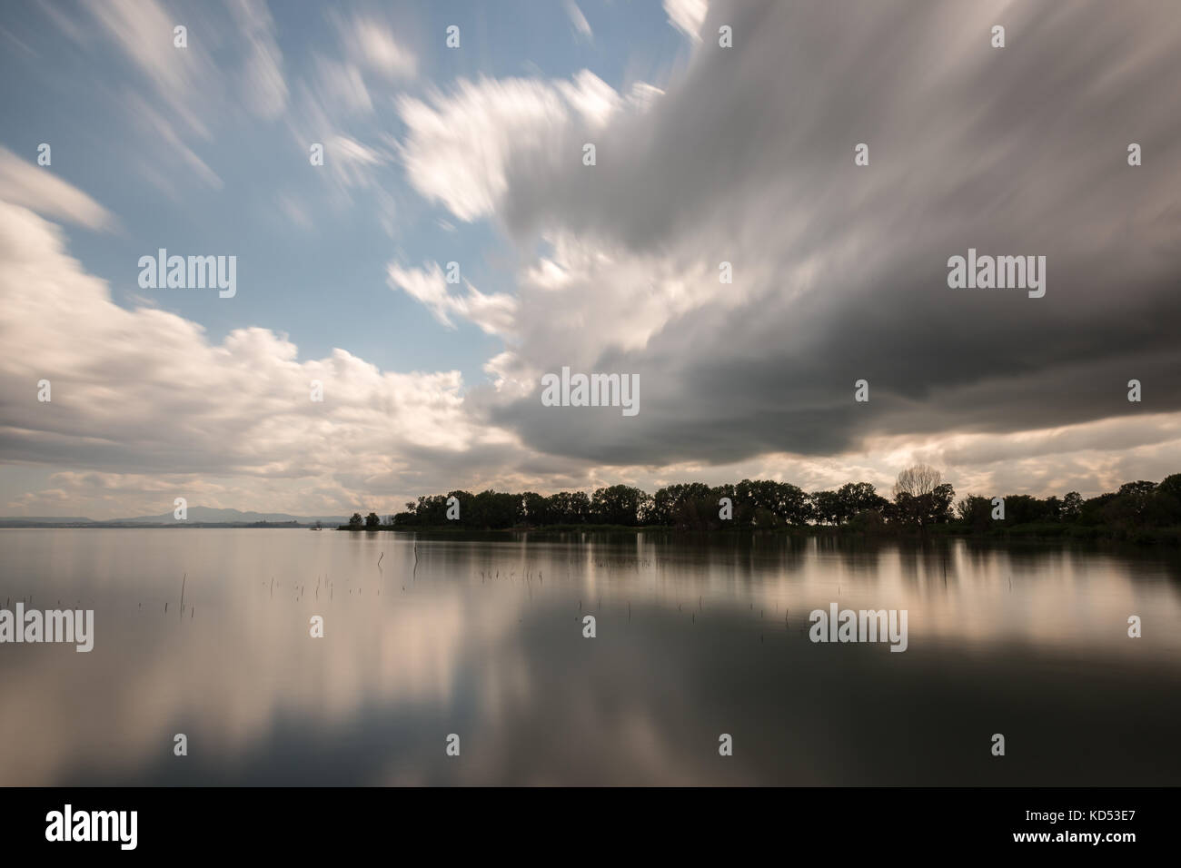 Langzeitbelichtung, Blick auf den See, mit beweglichen weißen Wolken perfekt auf dem Wasser widerspiegeln Stockfoto