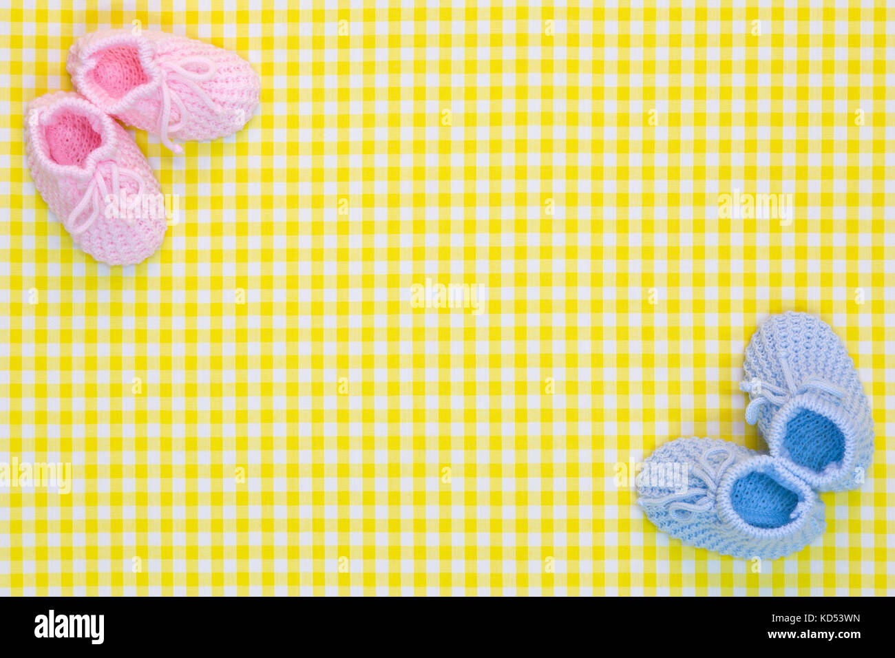 Kinitted baby Booties für ein Mädchen und ein Junge auf einem Gelb kariertem Hintergrund. Stockfoto