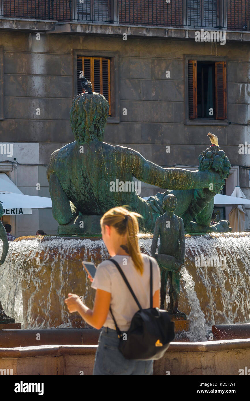 Frau reisen Solo-Konzept, Rückansicht einer jungen Frau navigieren per Telefon, während sie durch die Plaza de la Virgen in Valencia, Spanien. Stockfoto