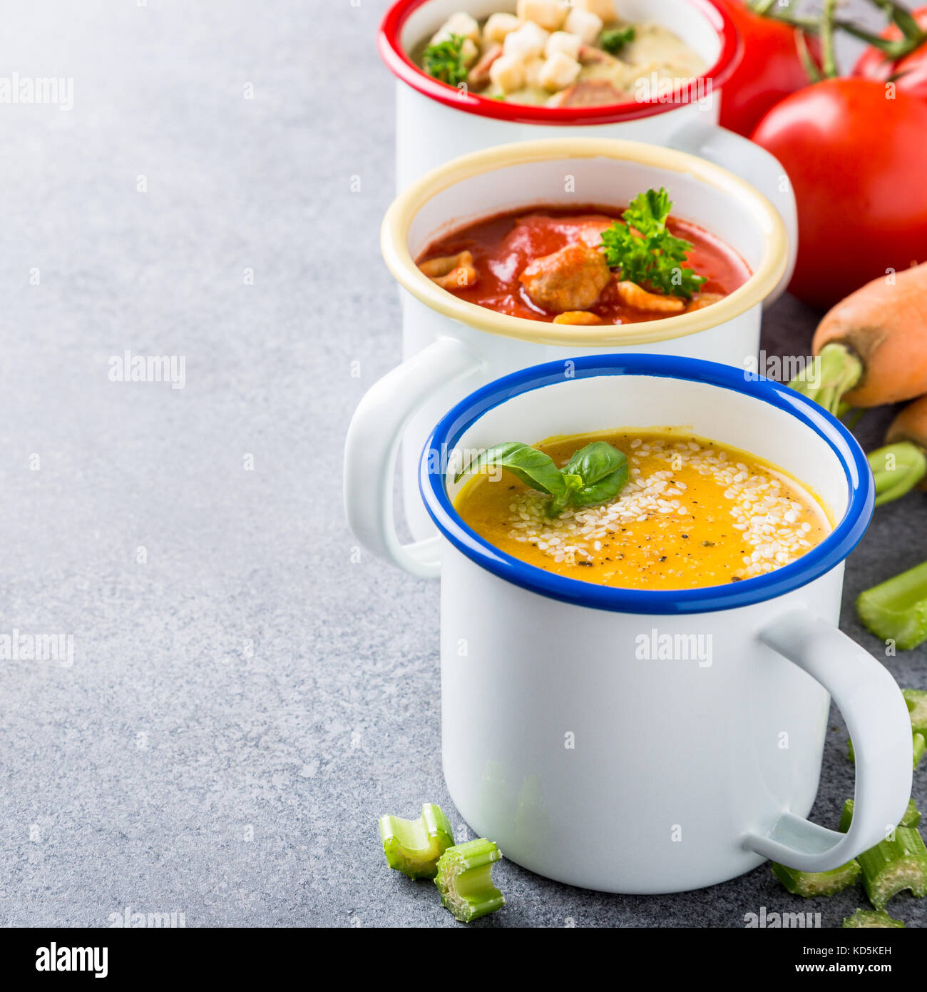 Verschiedene köstliche hausgemachte Suppen in Emaille Becher mit Zutaten. gesunde Ernährung Konzept mit kopieren. Stockfoto