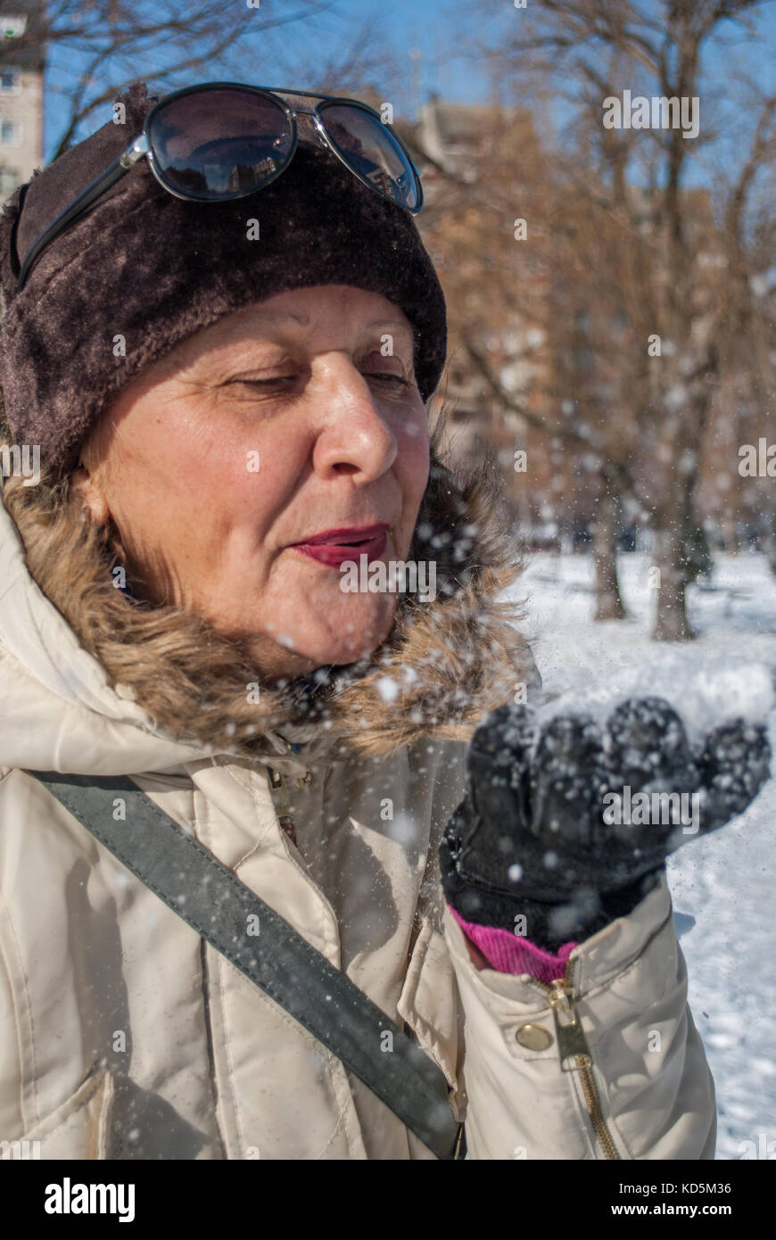 Frau mittleren Alters mit Brille in der Sonne, in den Schnee. Winter sonniger Tag Stockfoto