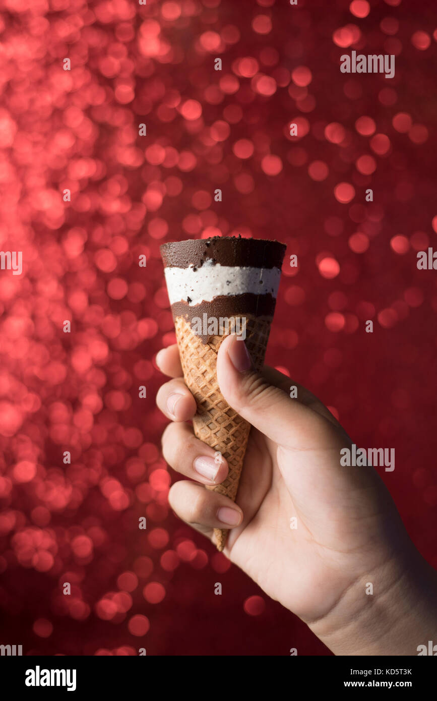 Hand/anzeigen Schokolade und Vanille Eis mit glänzenden roten Hintergrund Stockfoto