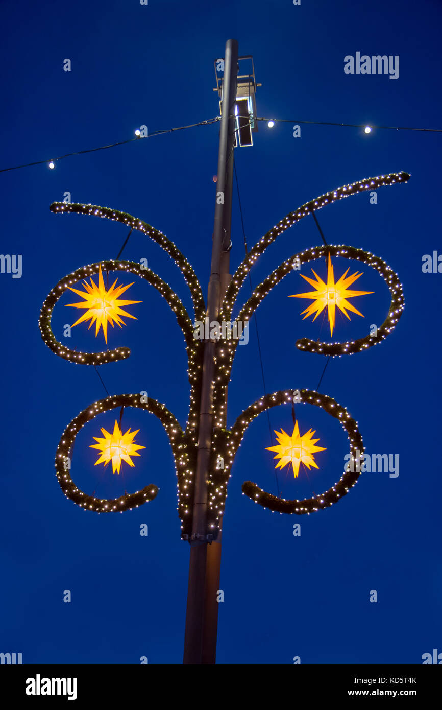 Die Lampe leuchtet in den Abendhimmel. Straßenlaterne mit Weihnachten Dekoration von Sternen und Glühlampen. Stockfoto
