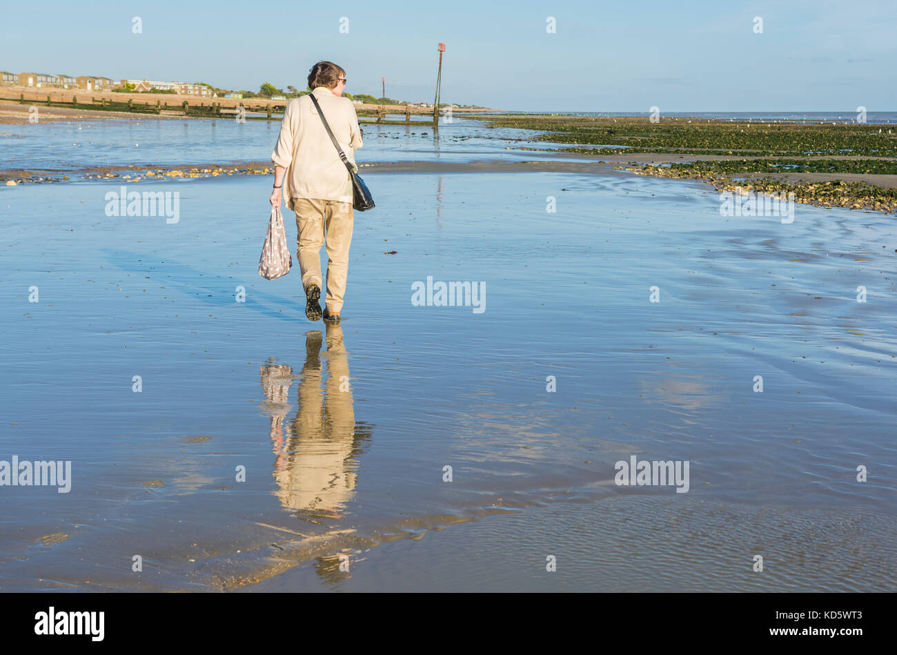 Frau aufwachen auf einem Strand bei Ebbe mit eine Reflexion ihrer im nassen Sand. Stockfoto