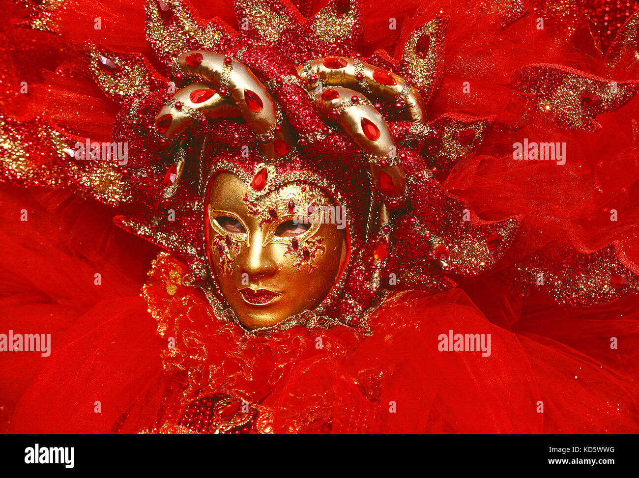 Italien. Venedig. Karneval. Person in rotem Kostüm. Nahaufnahme des Gesichts mit Goldmaske. Stockfoto