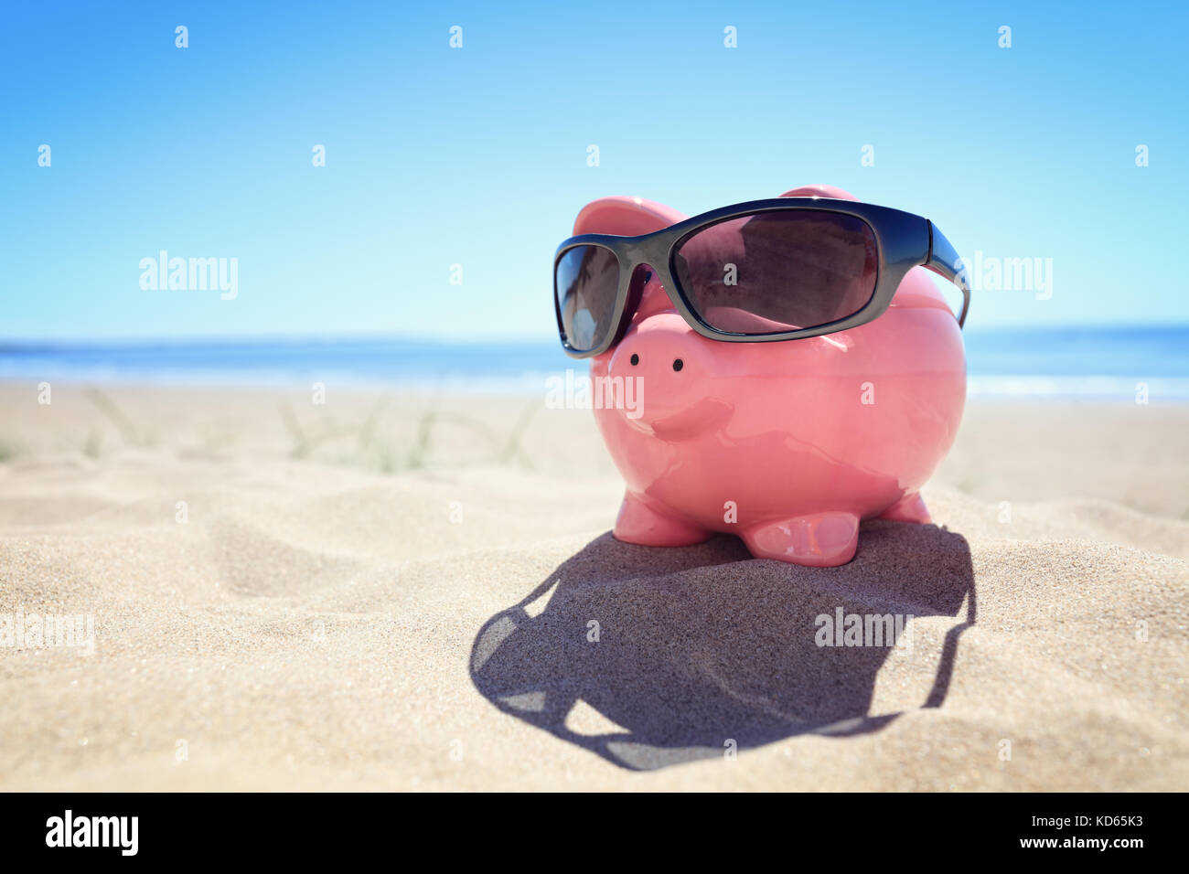 Sparschwein mit Sonnenbrille am Strand am Meer Stockfoto