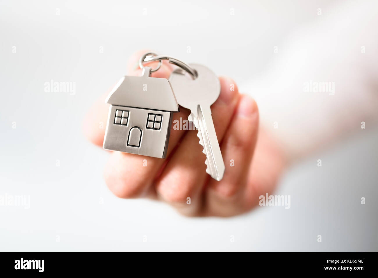 Das Halten von Hausschlüsseln auf einem Schlüsselanhänger-Konzept in Form eines Hauses für den Kauf eines neuen Hauses Stockfoto