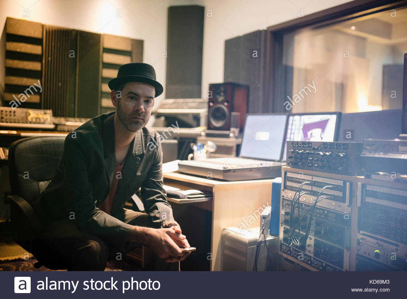 Portrait selbstbewusster männlicher Musiker, der mit dem Handy im Aufnahmestudio schreibt Stockfoto