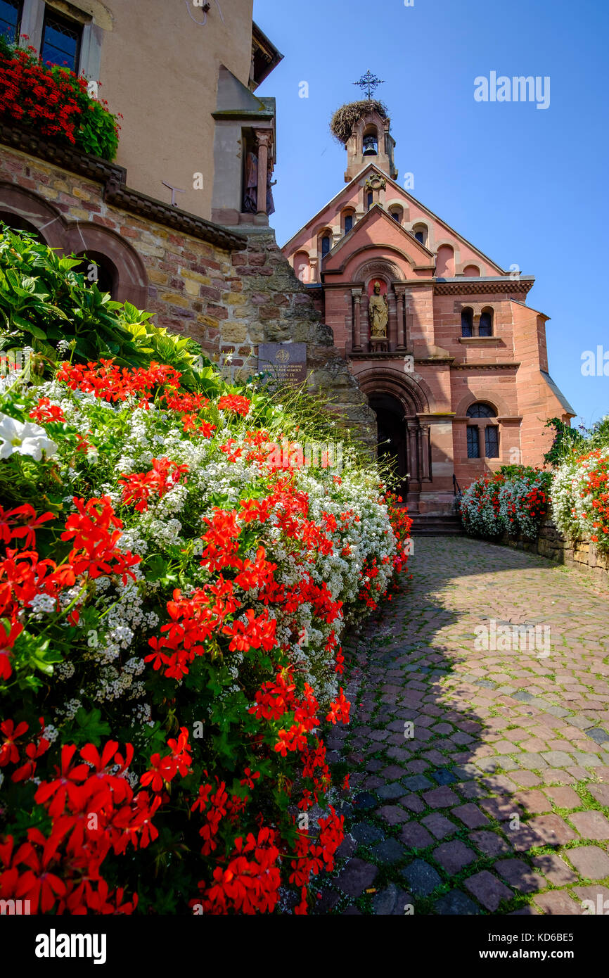 Eine kleine, mit Blumen dekoriert Straße führt zu einer kleinen Kirche im historischen Dorf Stockfoto