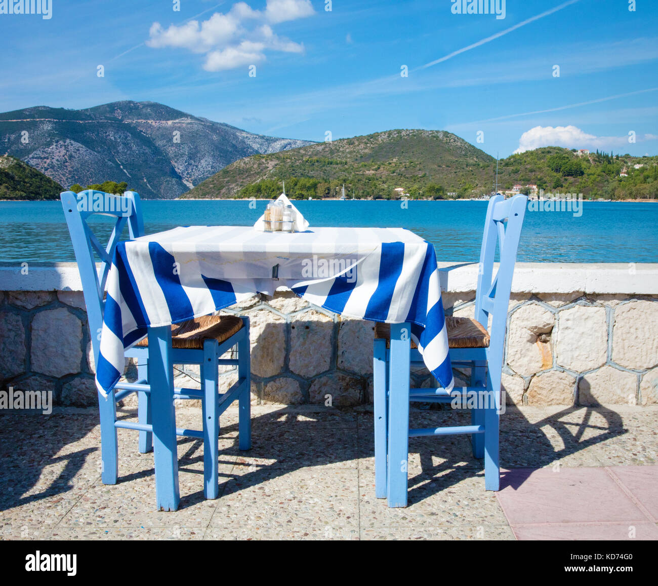 Blauer Tisch mit zwei Stühlen sowie griechische Flagge Tischdecke in einem Restaurant am Meer in Vathy, der Hauptstadt von Ithaka, Ionische Inseln Griechenland Stockfoto