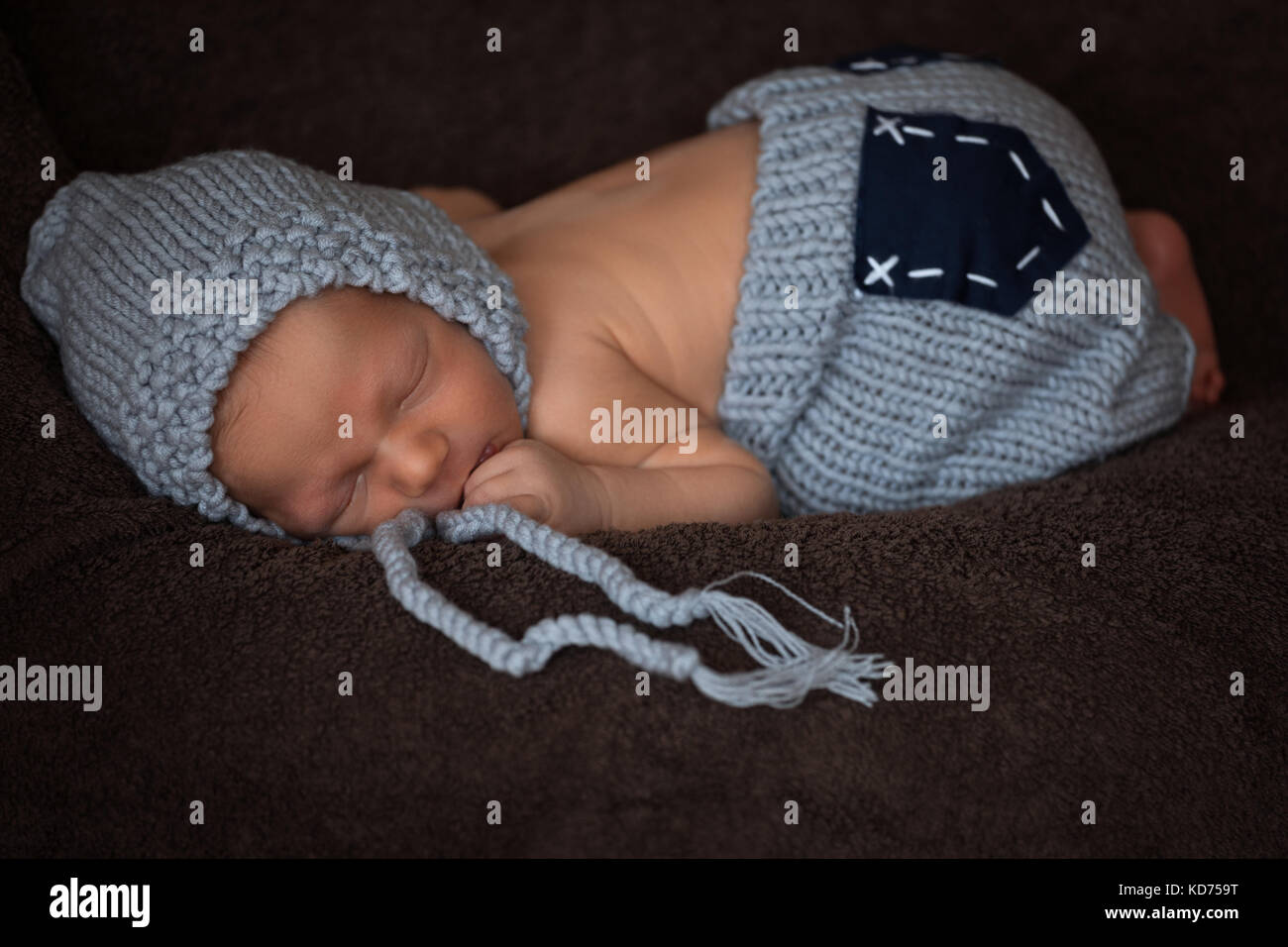 Neugeborenes Baby in einem grauen gestrickten Anzug schläft in einem schönen darstellen Stockfoto