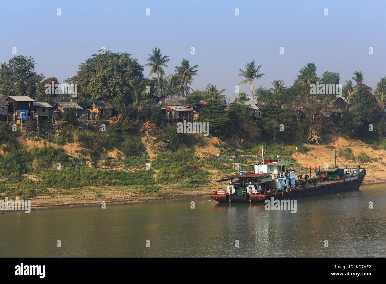 Häuser am Ufer des Minhla Village am Irrawaddy River in Myanmar (Burma). Ein Treibstoffkahn liegt am Ufer. Stockfoto