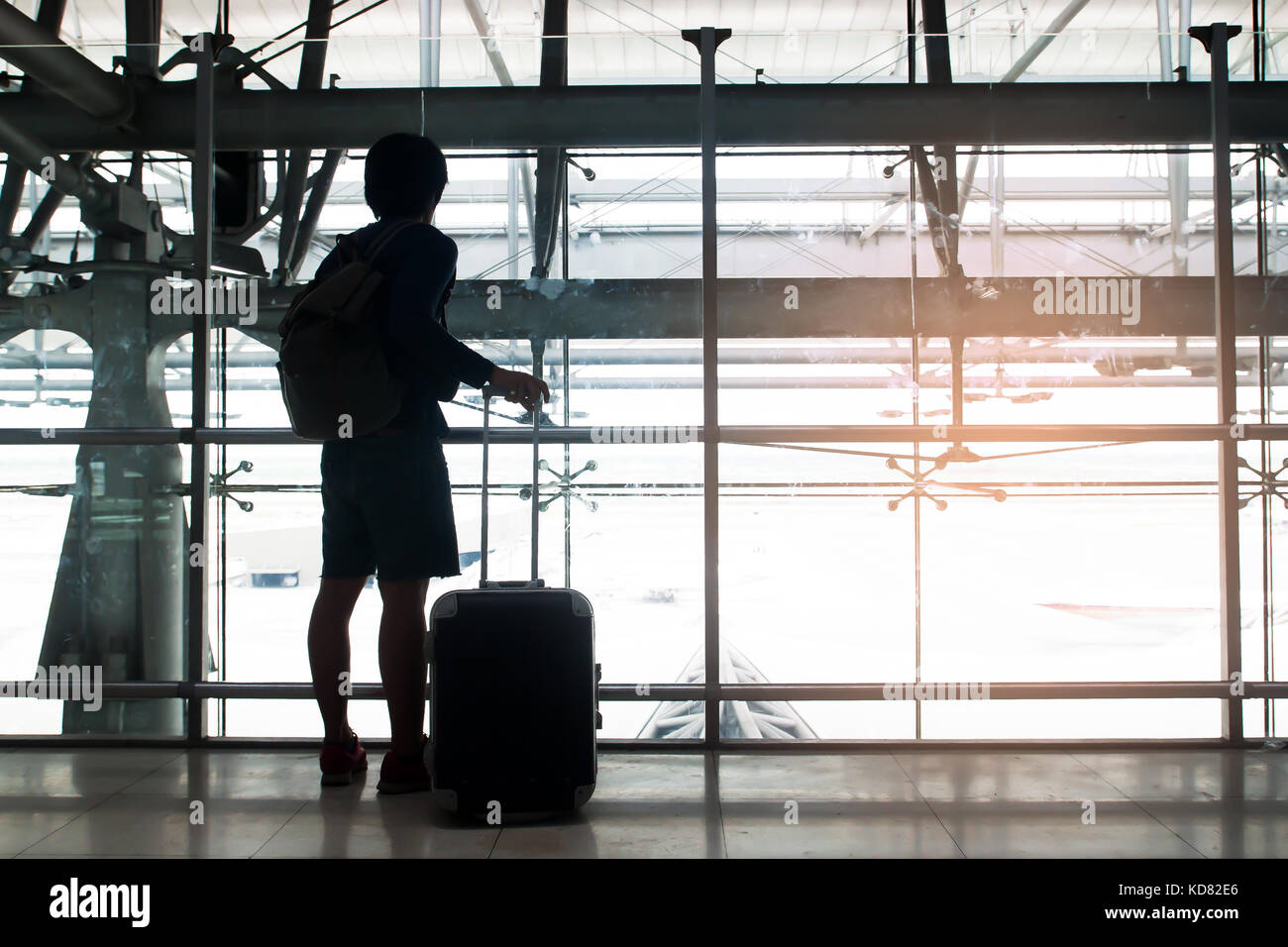 Silhouette eines Reisenden mit Gepäck Koffer und Rucksack Blick aus dem Fenster am Flughafen Stockfoto