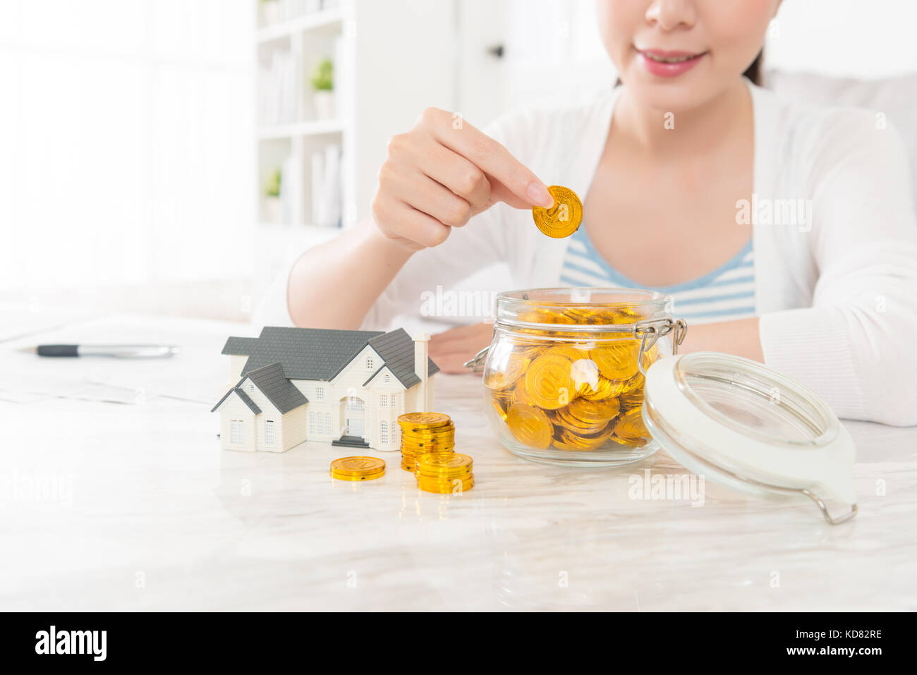Attraktive hübsche Frau mit Goldmünzen in Einsparungen bringen kann und Sie mit der Planung. Verwenden Sie Kaution Kauf neues Haus oder Immobilien investieren. Stockfoto