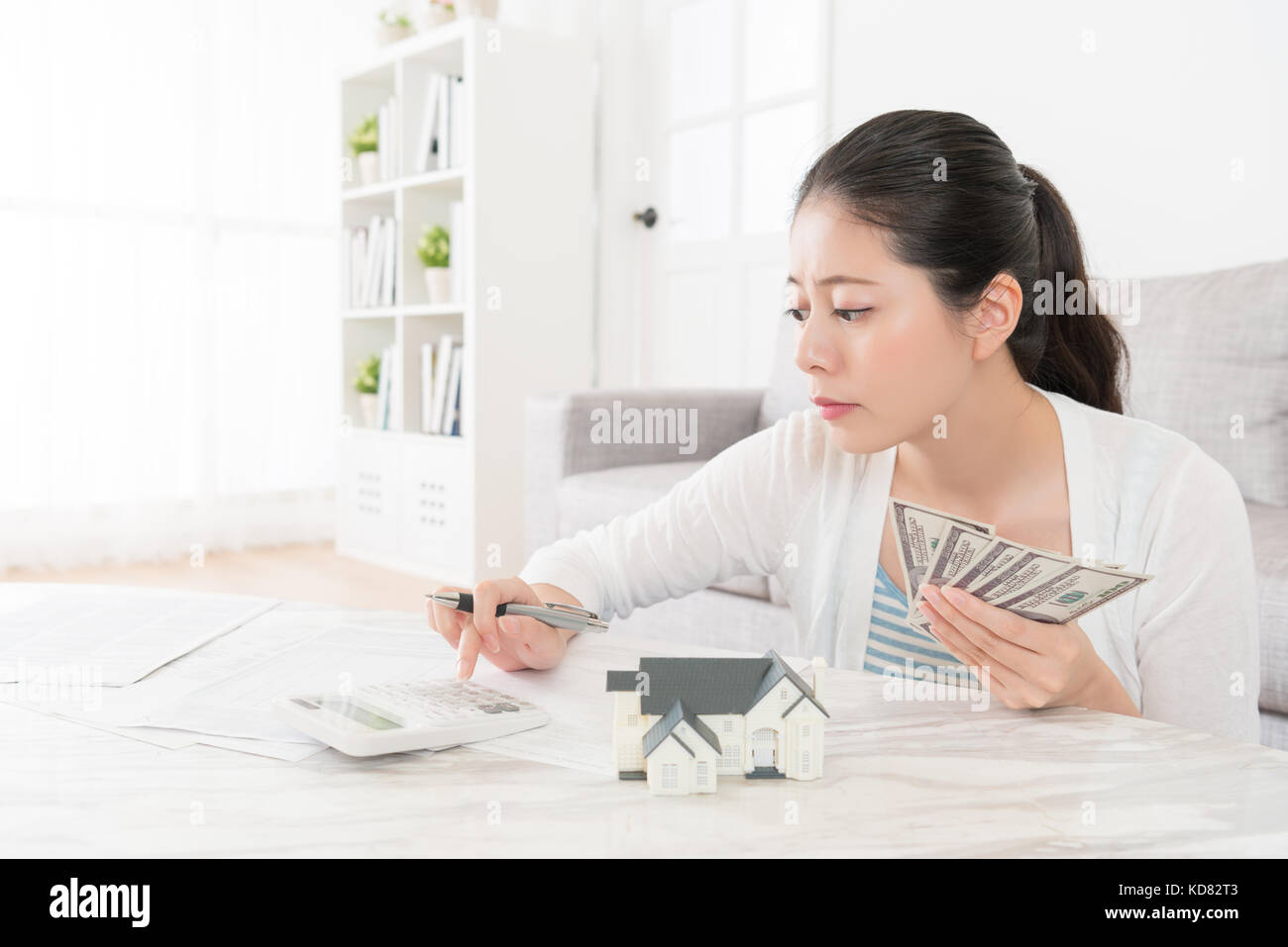 Schönheit süsse Frau mit Taschenrechner zählen ihre Ersparnisse Banknote im Wohnzimmer, wenn Sie zum Kauf neues Haus für Familie wünschen. Stockfoto