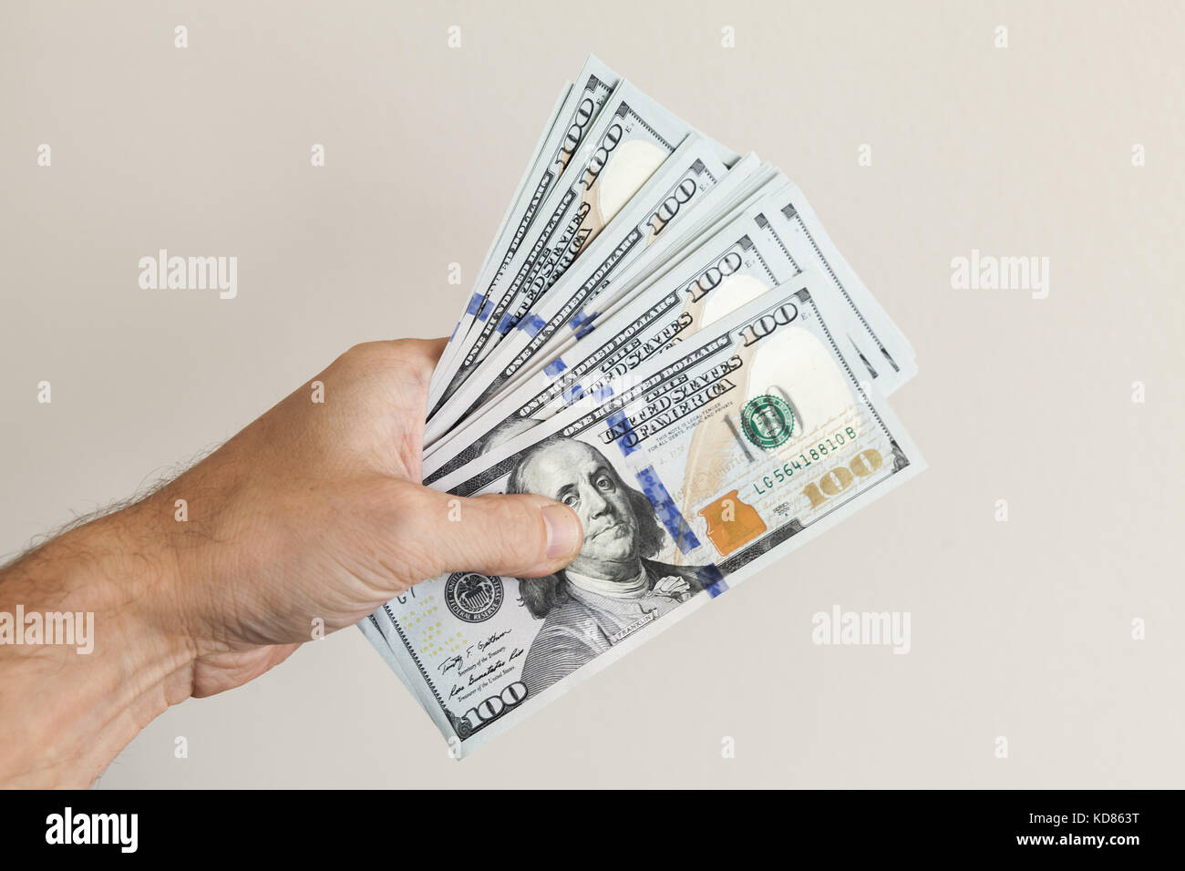 Fan von 100 Dollar Noten in männlicher Hand über graue Wand Hintergrund Stockfoto
