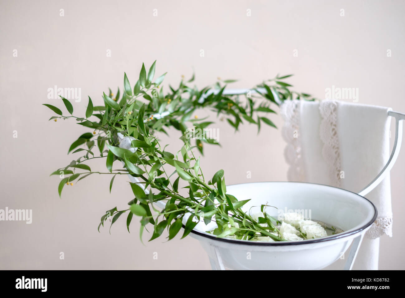 Äste und Rosen in einer Schüssel auf einem Metallständer Stockfoto