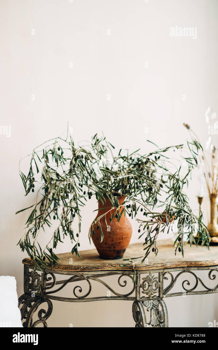 Olivenzweige in einer Vase neben einer Kerze auf einem Sideboard-Tisch Stockfoto
