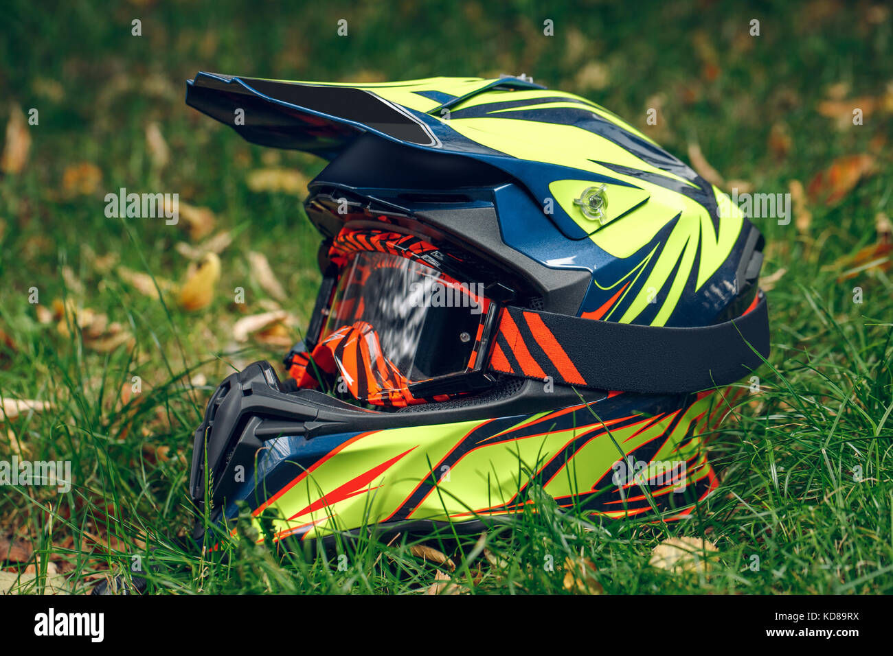 Motorrad Helm mit Brille zum Schutz trocken gefallenen Blätter über greem Gras. Automne Stockfoto