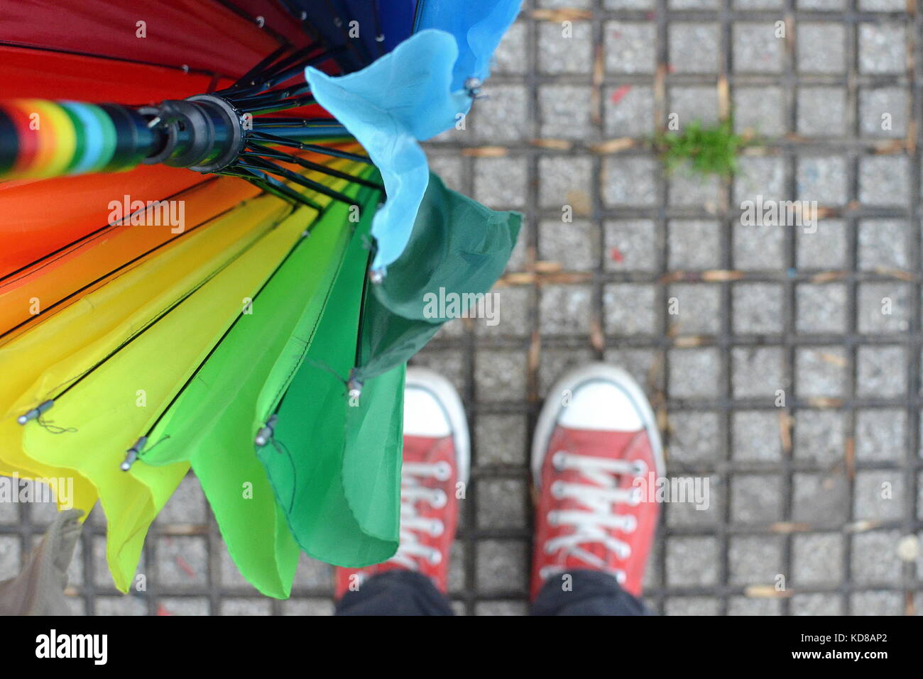 Frauenfüße und ein vielfarbiger Regenschirm Stockfoto