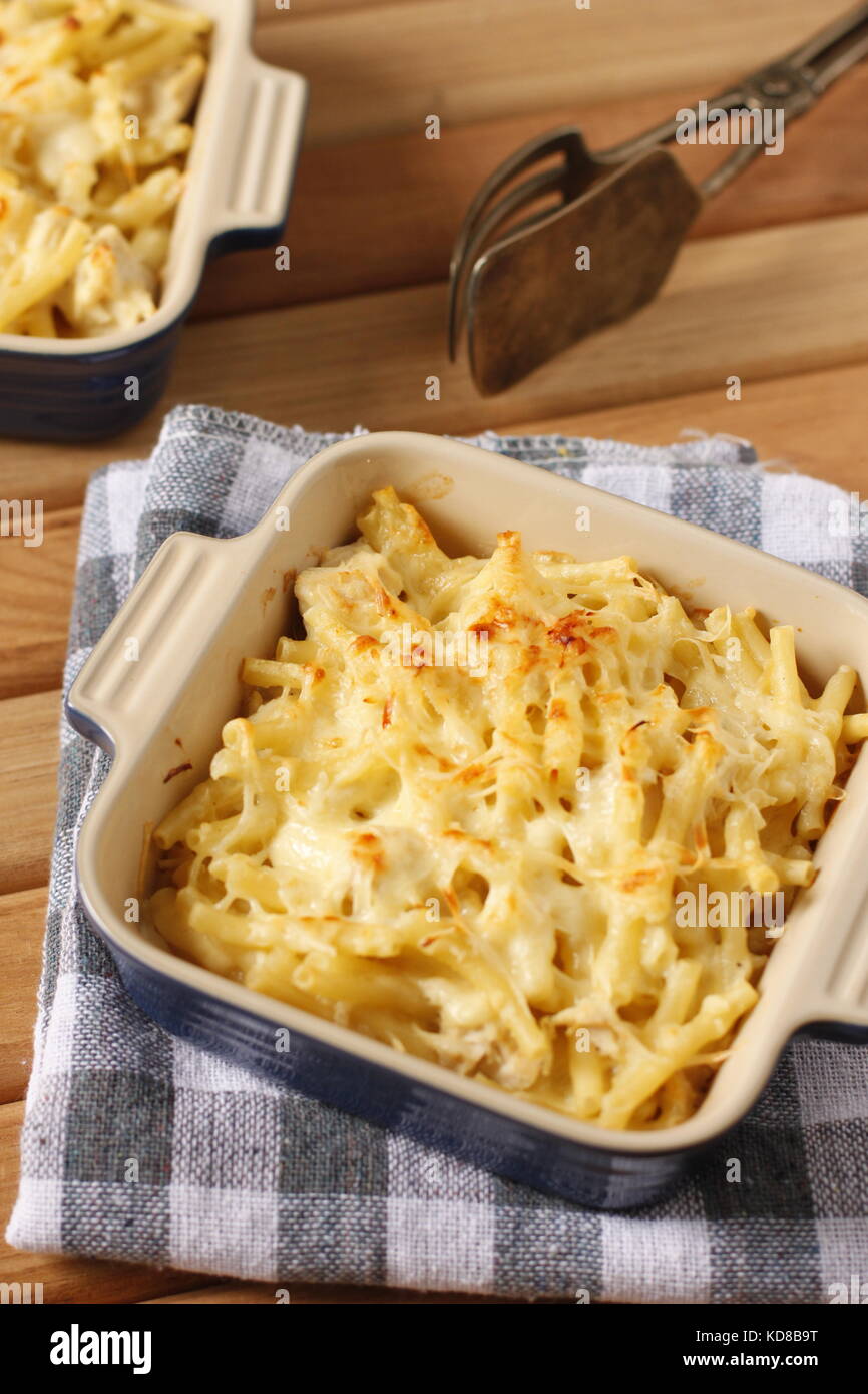 Mac und Käse in blau Backform über blau-weiß karierte Tuch mit alten Silber pasta Picker Stockfoto