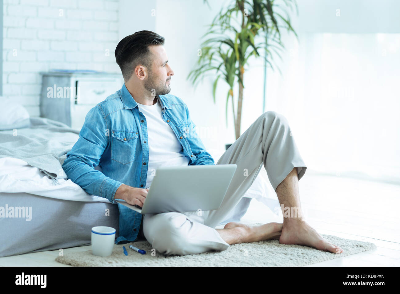 Nachdenklicher junger Mann träumen während der Arbeit am Laptop Stockfoto