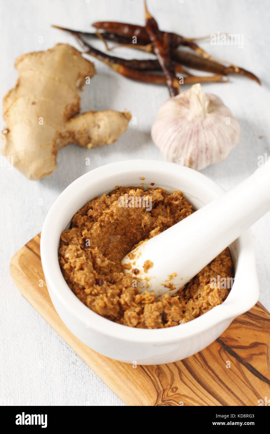 Currypaste auf einem weißen Mörtel mit Knoblauch, Chili und Ingwer Stockfoto