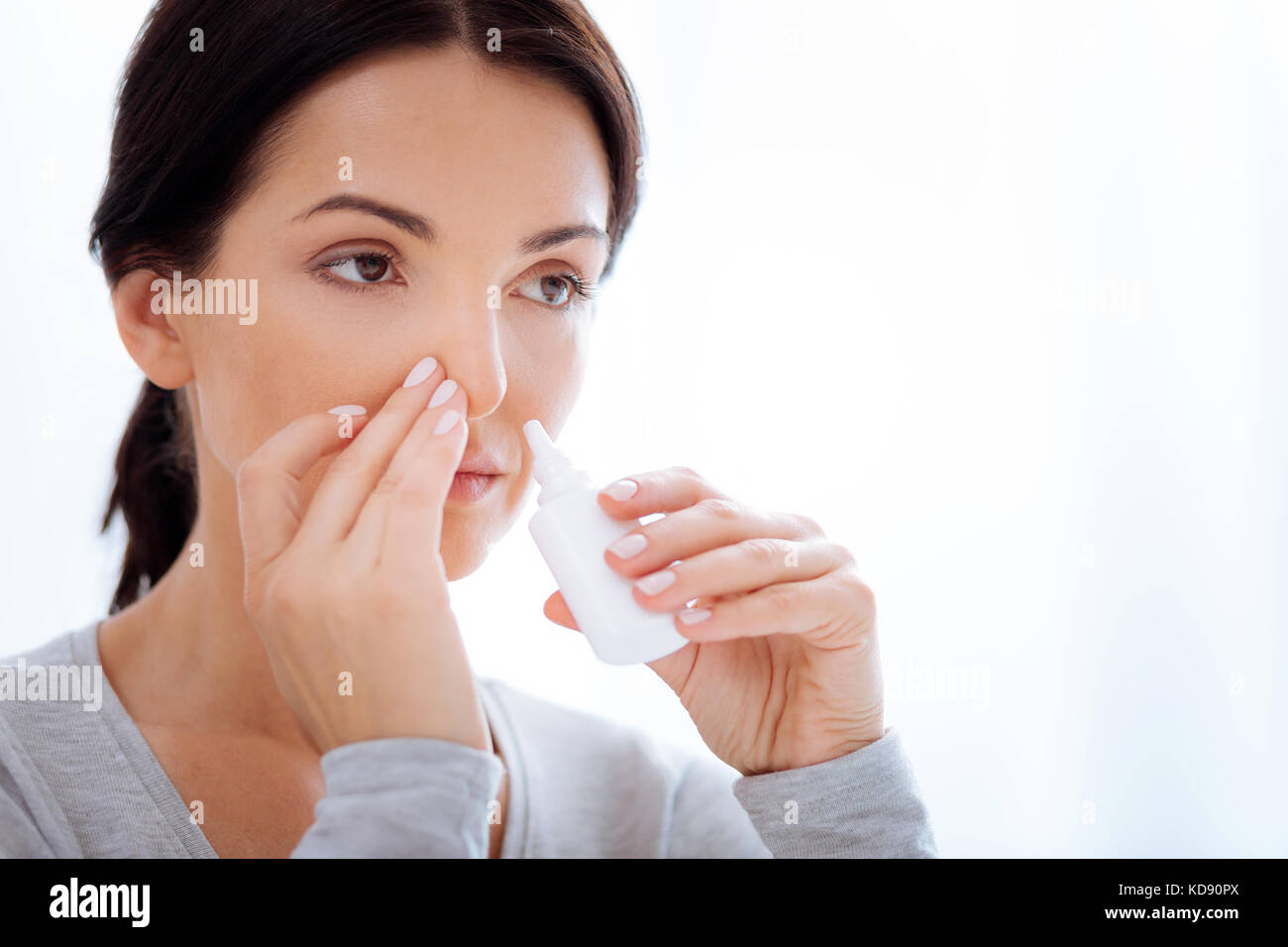 Aufmerksame Frau mit speziellen Nasentropfen Stockfoto