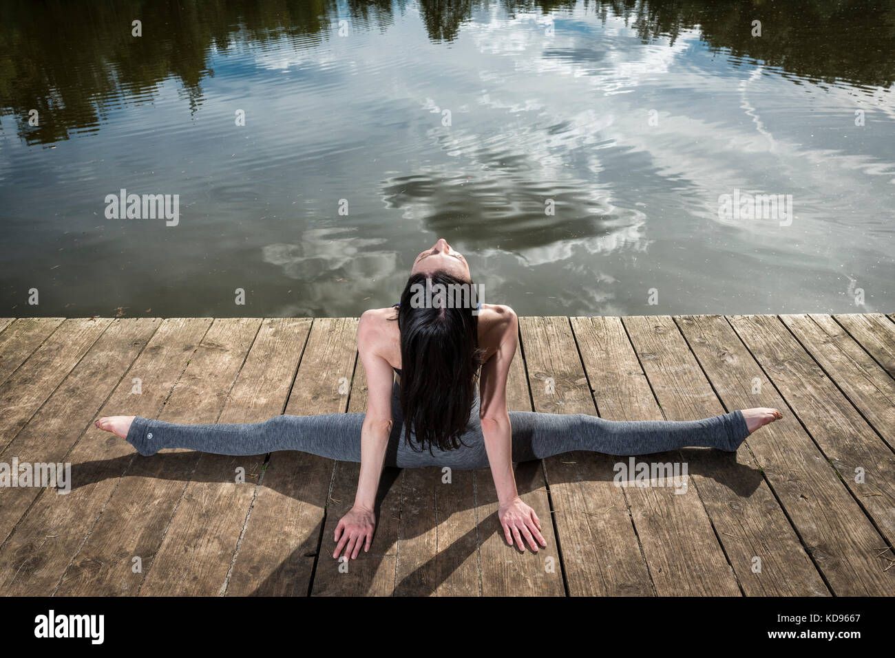 Frau vollen Splits auf einem Steg am Wasser Stockfoto