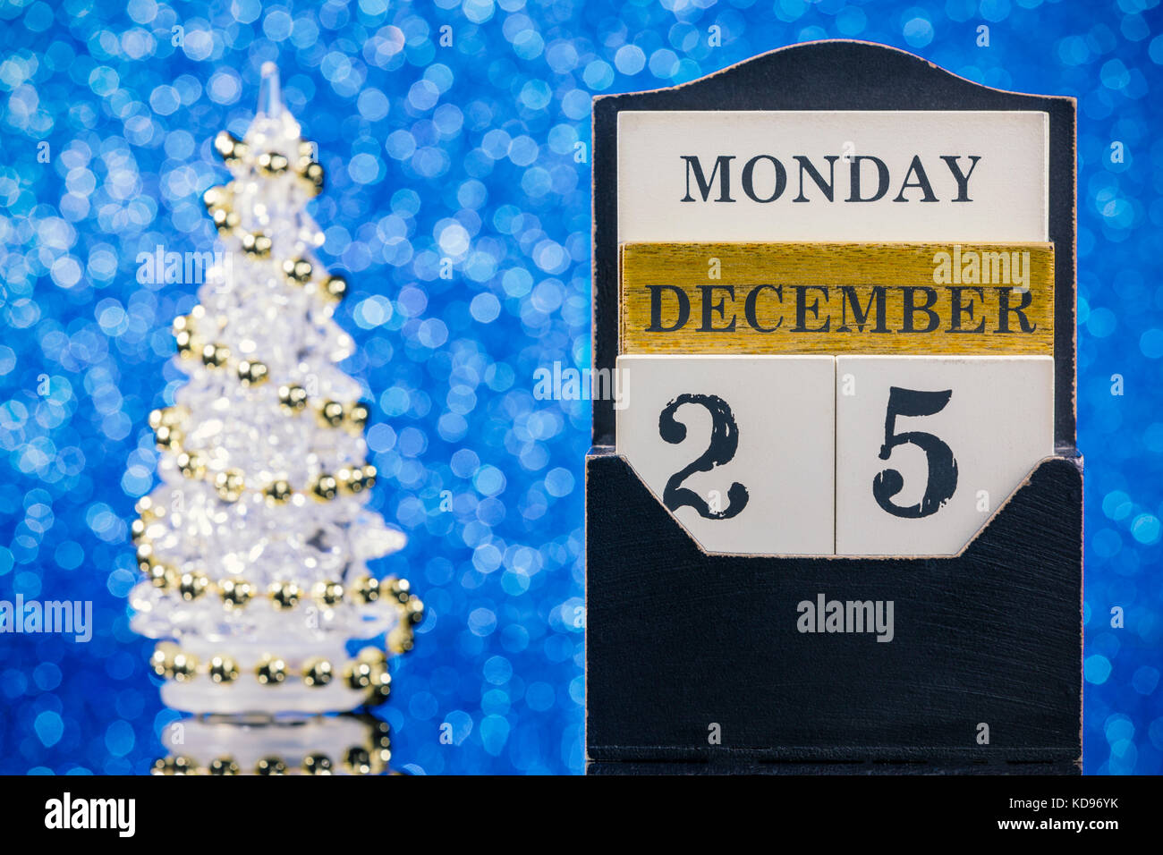 Holz- Kalender und Weihnachtsbaum Reflexionen auf Glas Tisch über blauer Hintergrund Stockfoto