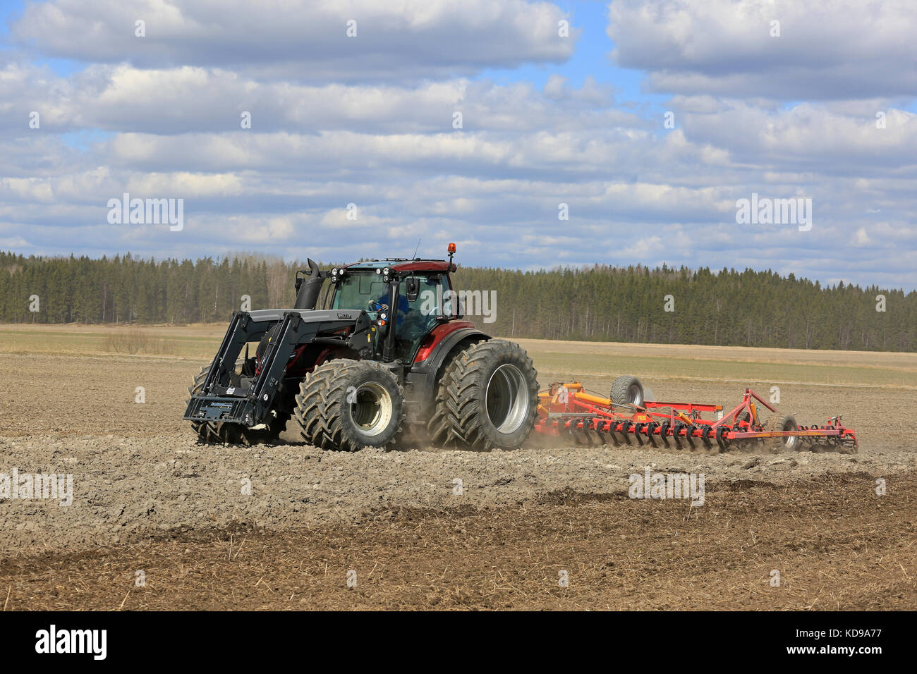 SALO, FINNLAND - 7. MAI 2017: Der rote Valtra-Traktor und der Potila-Saatbettzüchter kultivieren an einem schönen Frühlingstag das Feld. Stockfoto