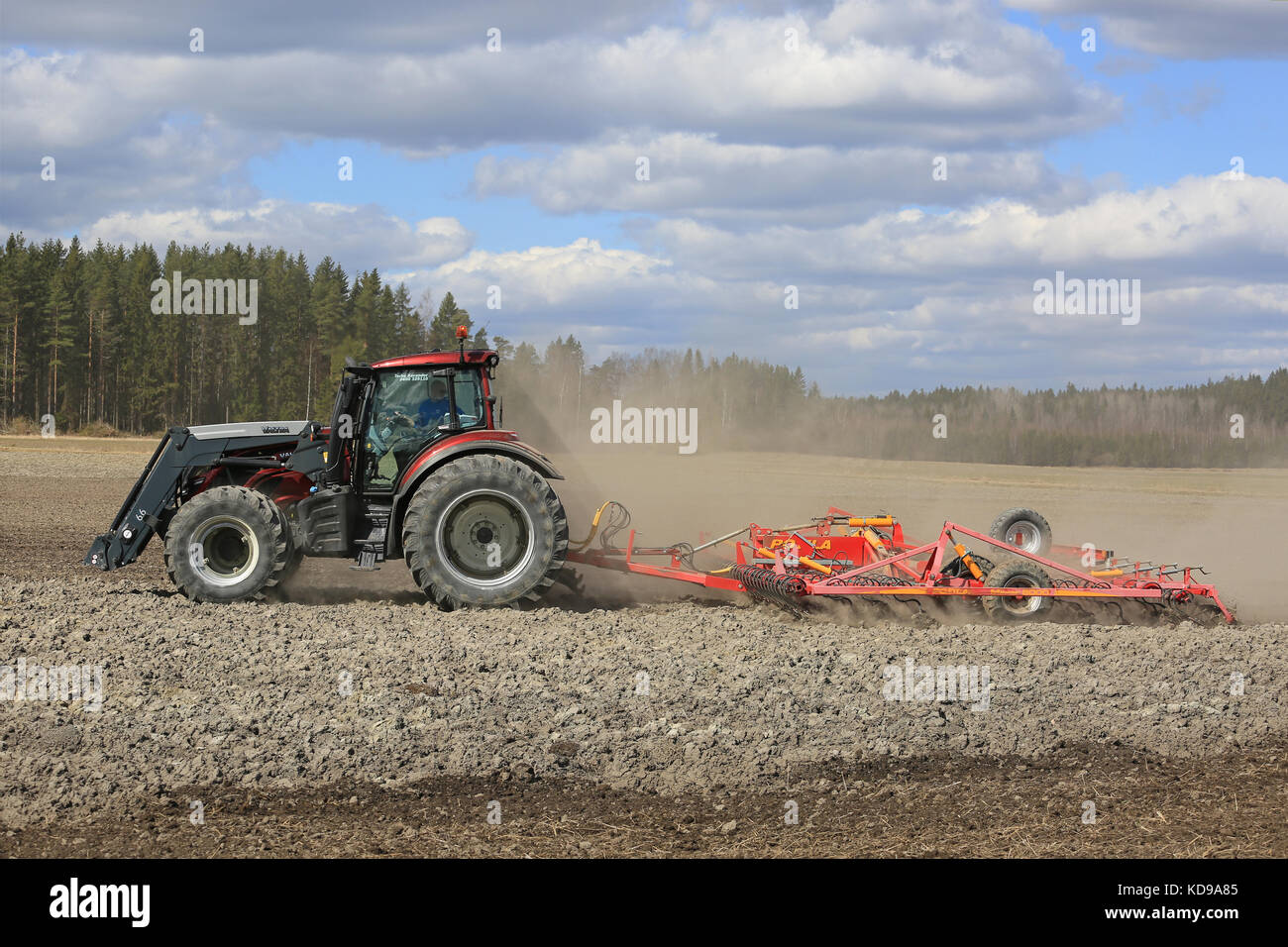 SALO, FINNLAND - 7. MAI 2017: Landwirt bewirtschaftet an einem schönen Frühlingstag Feld mit rotem Valtra-Traktor und Potila-Saatbettzüchter. Stockfoto