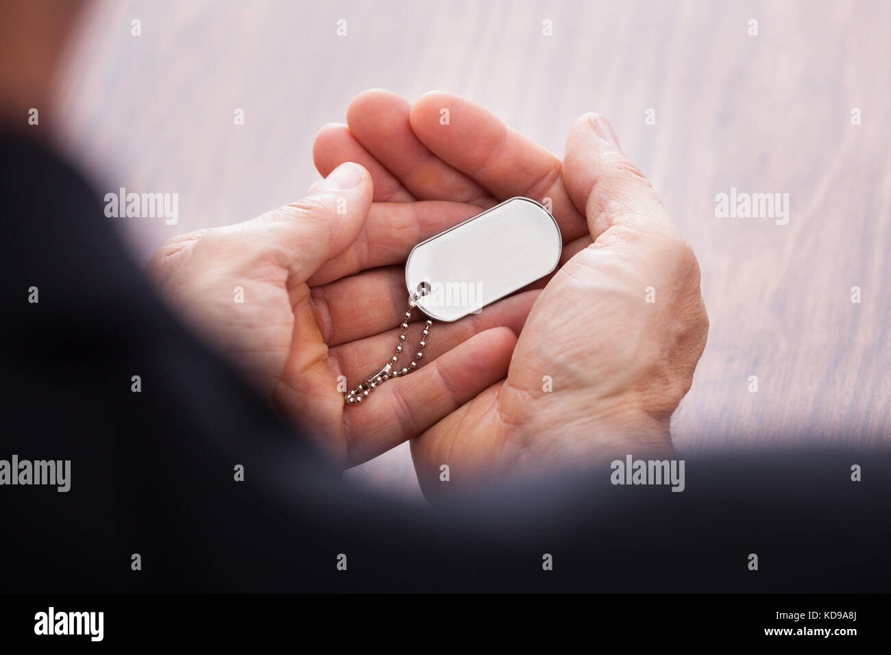 Nahaufnahme der Geschäftsmann hand auf Holztisch holding Dog Tag Stockfoto