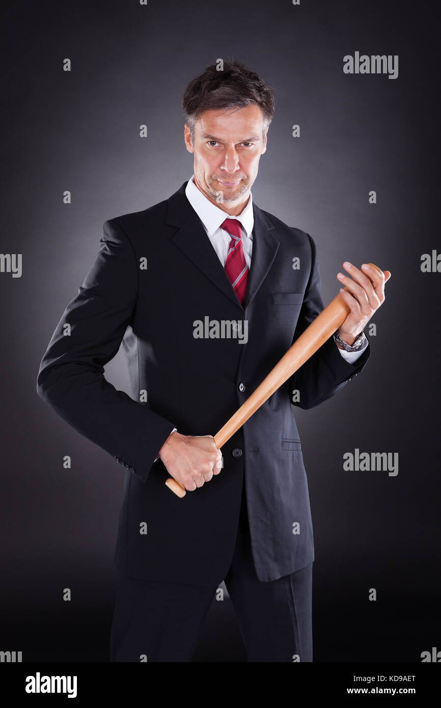 Portrait von Reifen Geschäftsmann holding Baseballschläger auf schwarzem Hintergrund Stockfoto