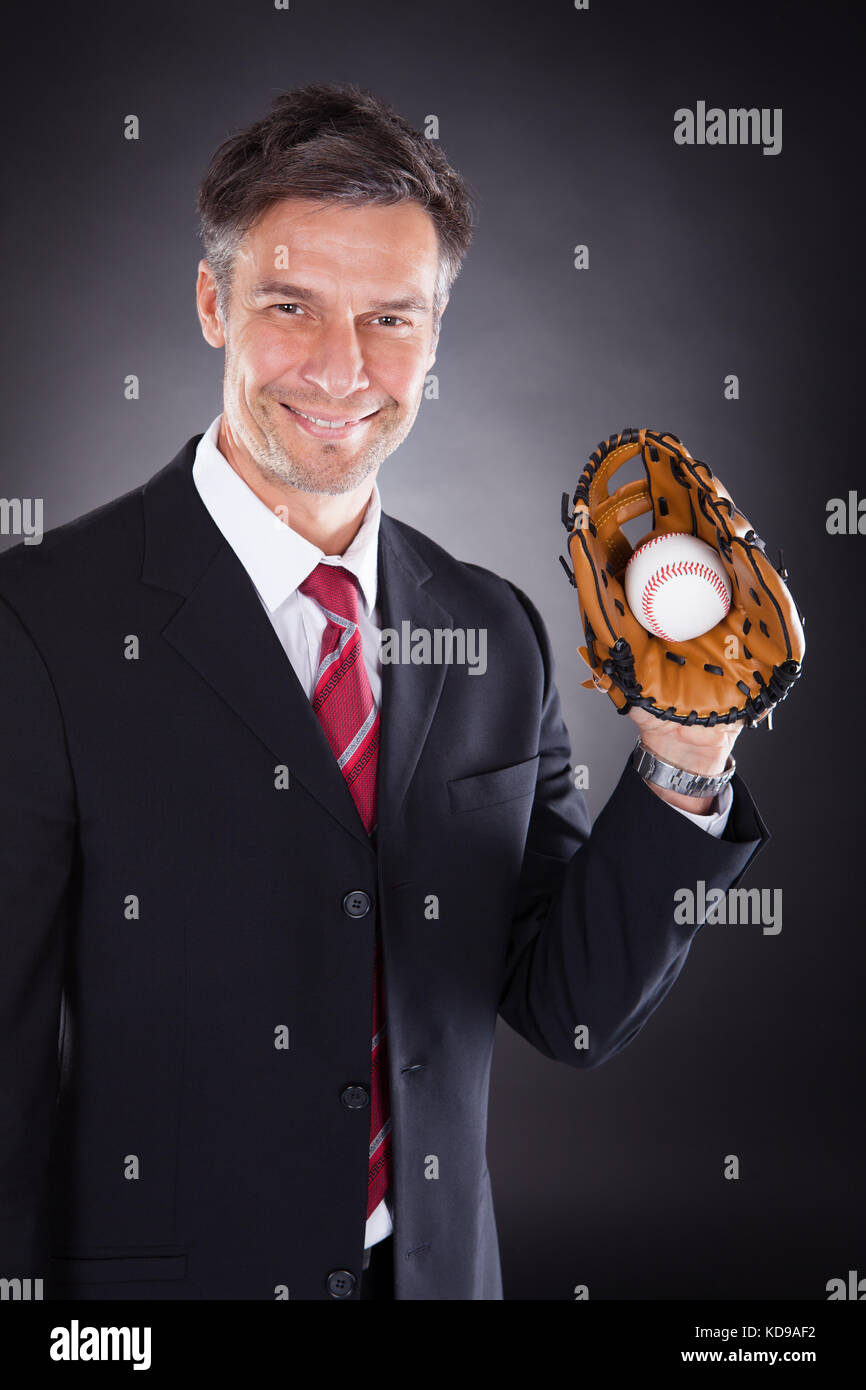 Gerne reife Geschäftsmann holding Baseball und mitt auf schwarzem Hintergrund Stockfoto