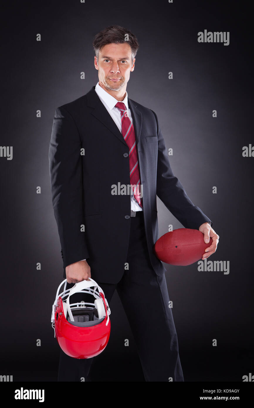 Reifen Geschäftsmann halten roten Rugby Helm auf schwarzem Hintergrund Stockfoto