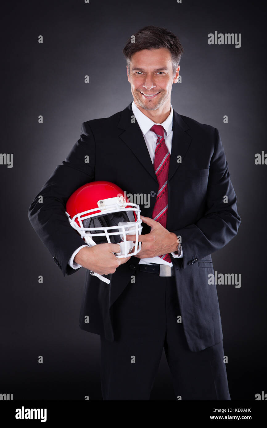 Reifen Geschäftsmann halten roten Rugby Helm auf schwarzem Hintergrund Stockfoto