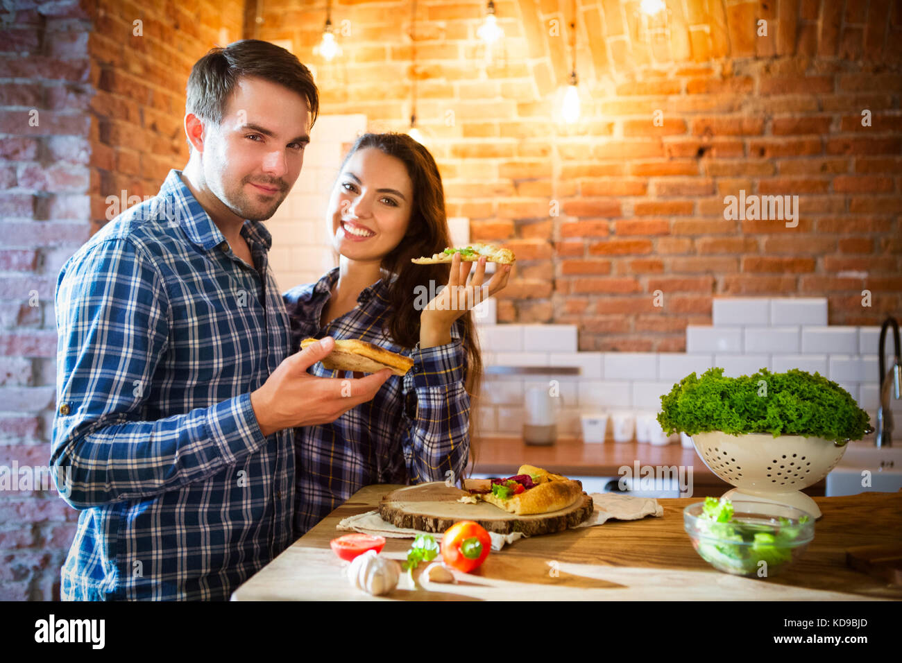 Junge lächelnde Paar hausgemachte Pizza essen zusammen an Küche Stockfoto