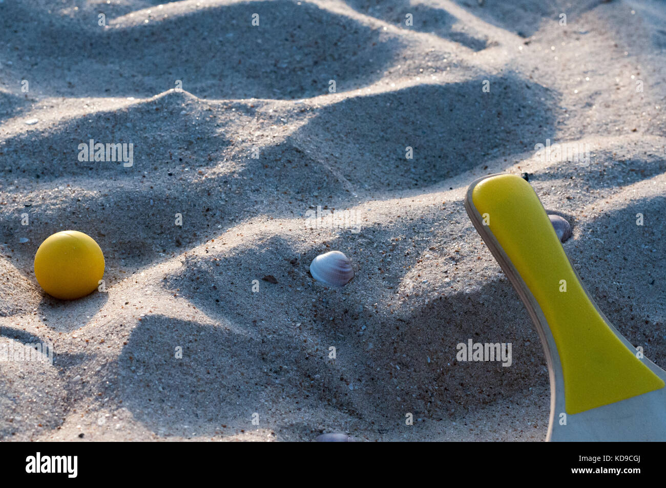 Paddel und gelbe Kugel auf einem Sandstrand Stockfoto