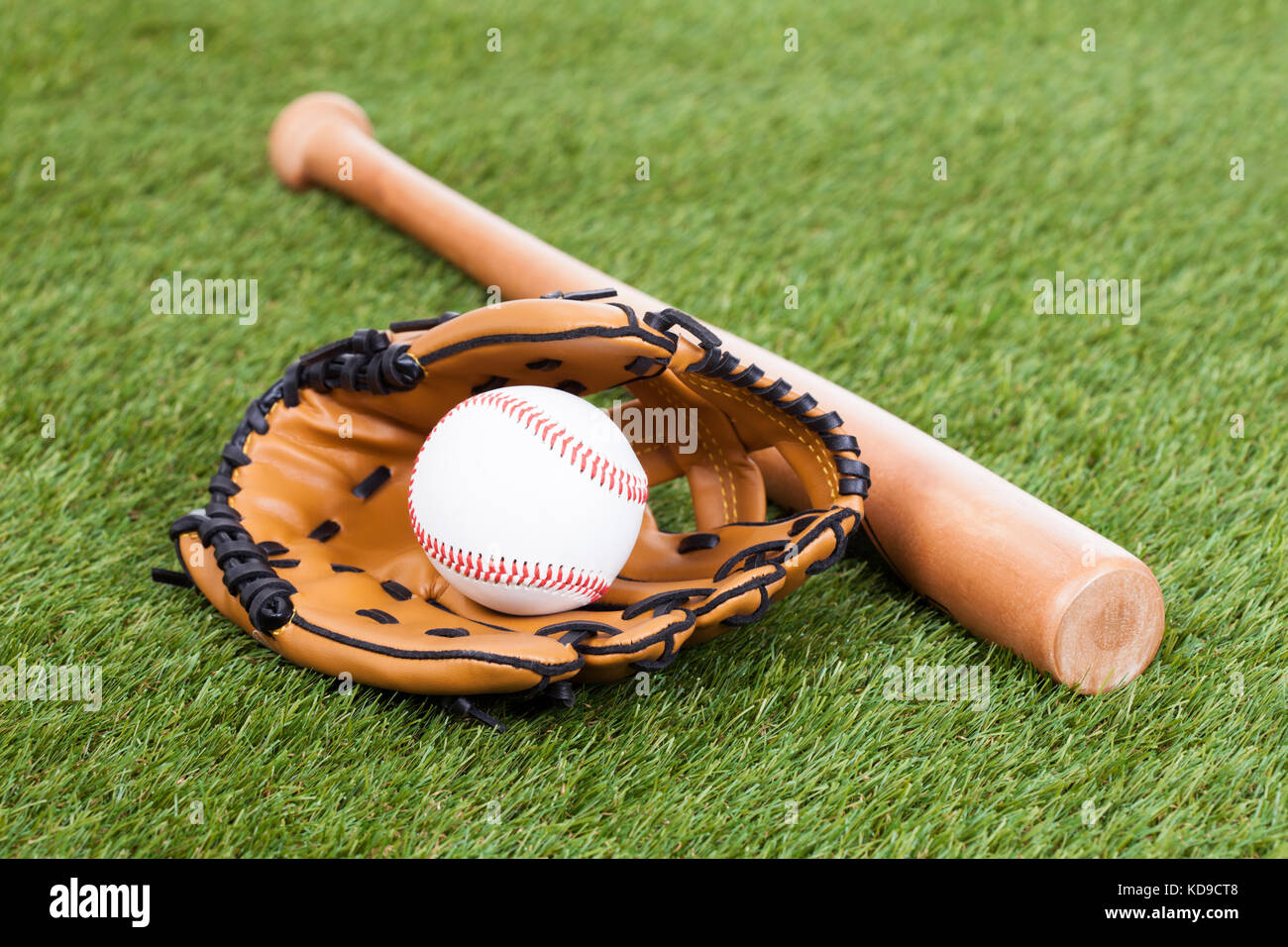 Leder-Handschuh mit Baseball und Bat auf grünen Rasen Stockfoto
