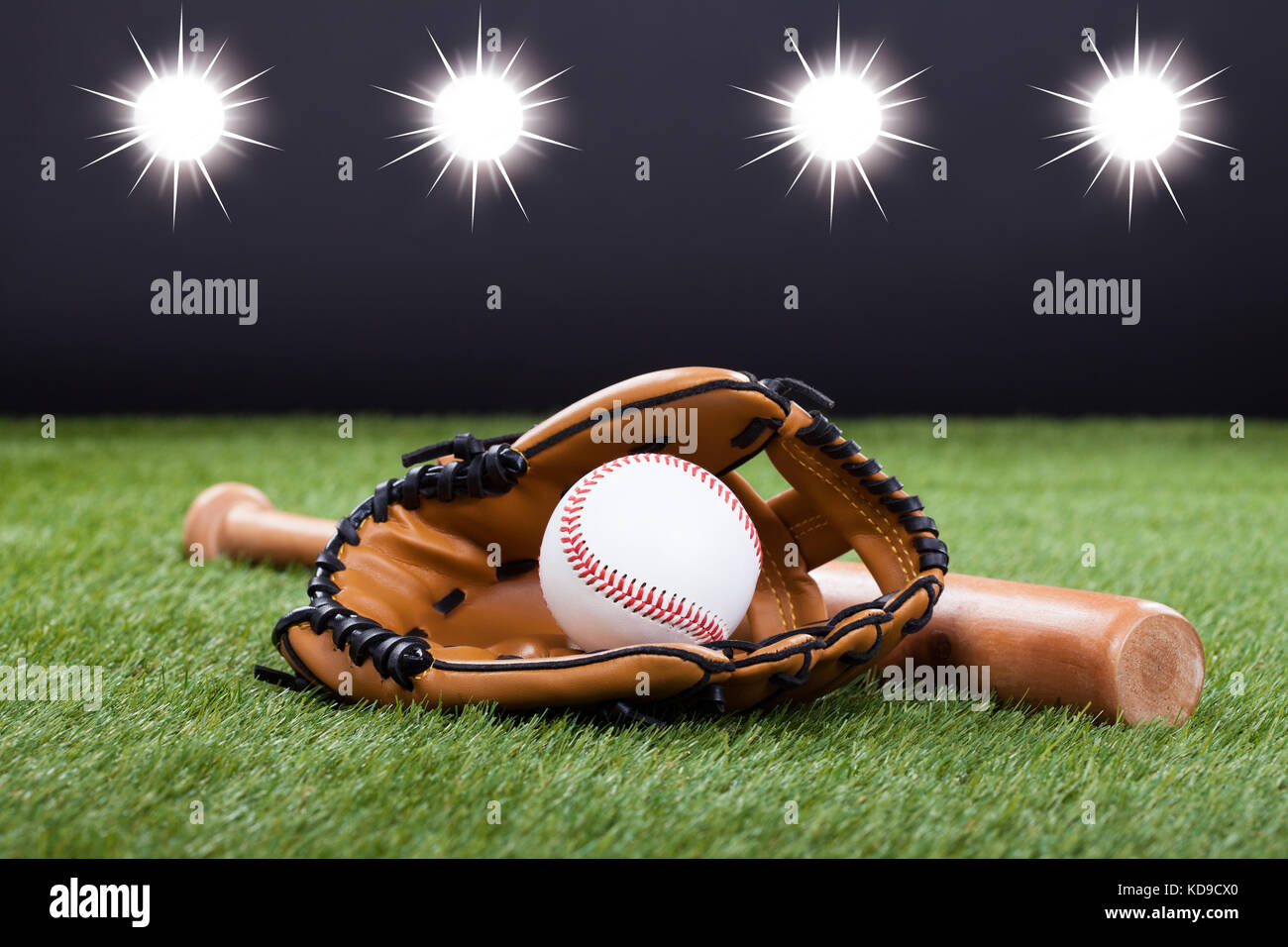 Baseball-Handschuh mit Baseball und Bat liegend auf dem grünen Rasen Stockfoto