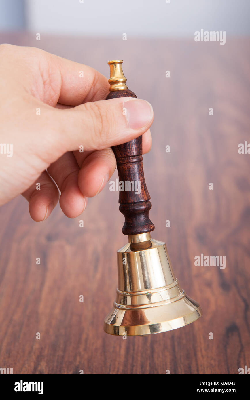 Nahaufnahme der Person Hand auf Holztisch mit Glocke Stockfoto