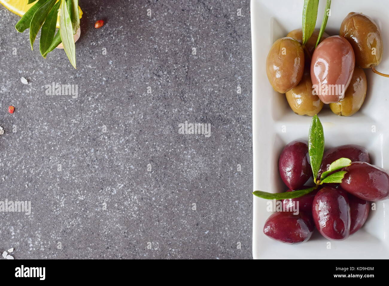 Platte der schwarze und grüne Oliven auf einem grauen Abstrakt Hintergrund mit der Kopie Raum. gesunde Ernährung Konzept Stockfoto
