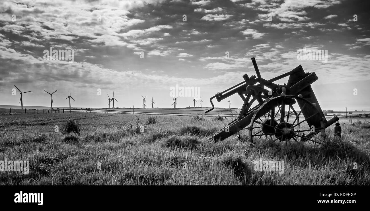 Alte und neue Technik - Windenergieanlagen und verlassenen Pflug - Schwarz und Weiß Stockfoto