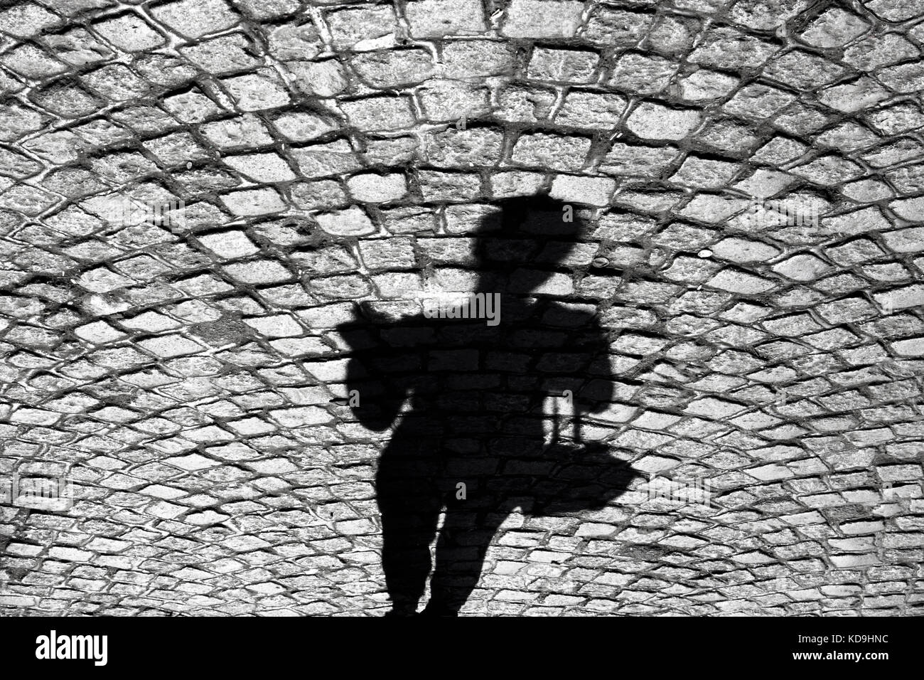 Verschwommene Schatten einer Frau, die zu Fuß auf dem alten Kopfsteinpflaster Stockfoto
