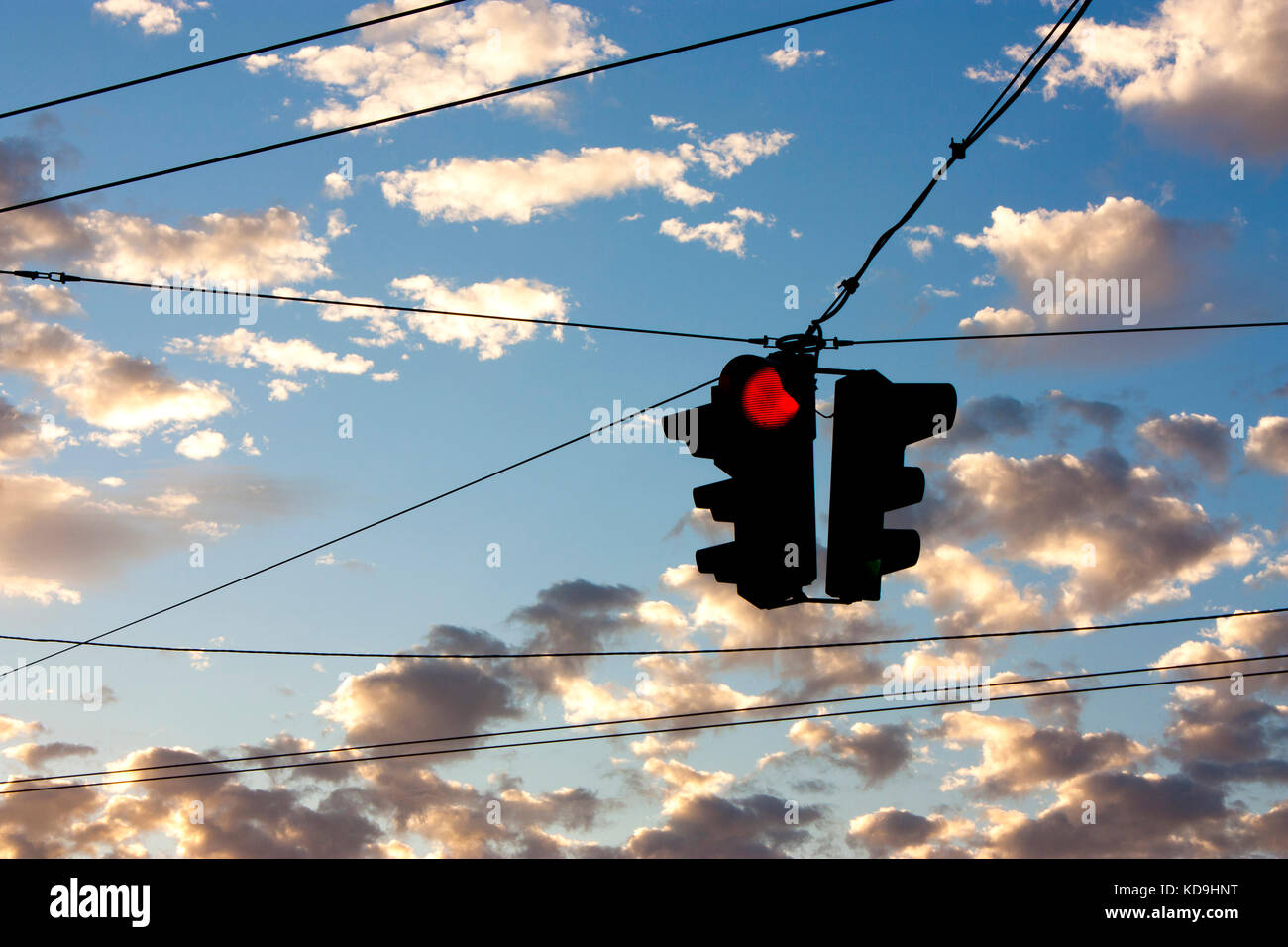 Silhouette der rote Ampel gegen den blauen Himmel mit kleinen Wolken bei Sonnenuntergang Stockfoto